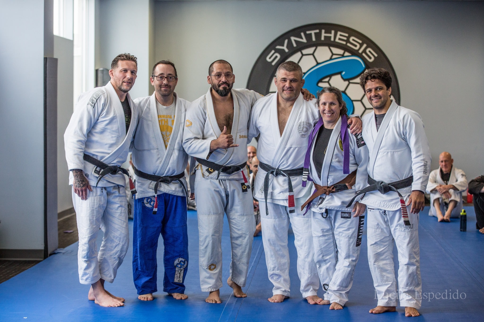 Instructors stand for a group photo in front of the logo